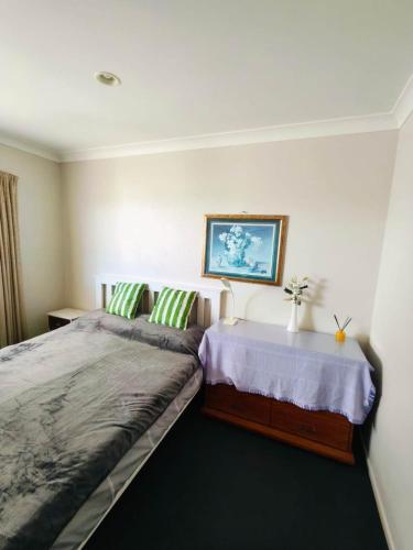 a bedroom with a bed with two green pillows at Bayview Holiday Flat in Auckland
