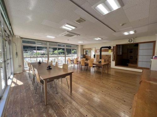 a room with tables and chairs in a building at 山村自然楽校しもなの郷 Simona no Sato Riverside Old School Retreat in Nanokawado