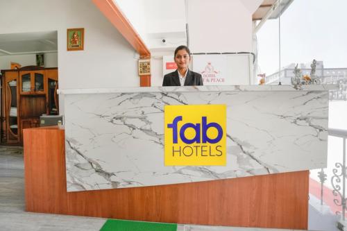 a man standing behind a counter with a fico hotel sign at FabHotel Rest & Peace in Ahmedabad