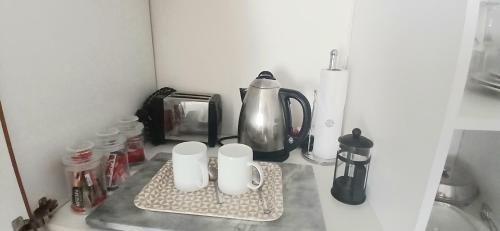 un bancone della cucina con due tazze e un bollitore per il tè di Shark Cove Little Cottage a Kleinbaai