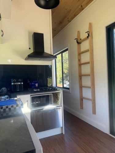 a kitchen with a stove and a stove top oven at Ferncroft Farm Tiny Home Berry in Wattamolla