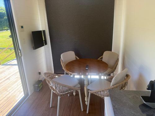 a table and chairs and a table and a door at Ferncroft Farm Tiny Home Berry in Wattamolla