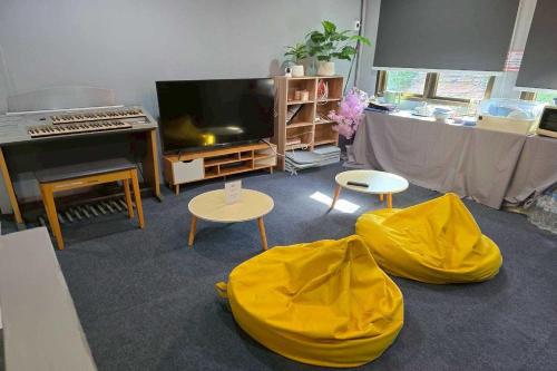 a living room with a television and two tables and a piano at Sukhum Huai Khwang Guest House in Bangkok