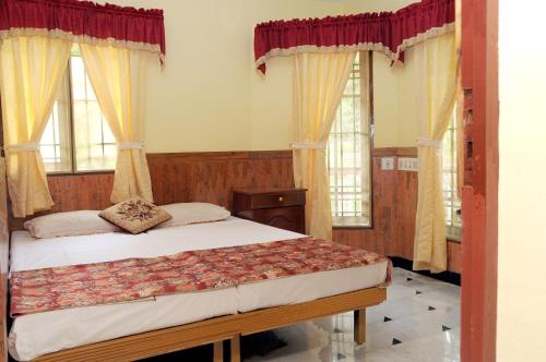 a bedroom with a bed and two windows at Maison Casero Home Stay in Cochin