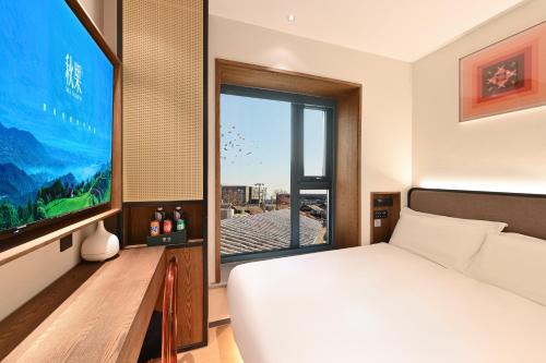 a bedroom with a bed and a large screen television at QiuGuo Hotel Chao He Beijing Dashilan Xijie Qianmen Subway Station Branch in Beijing