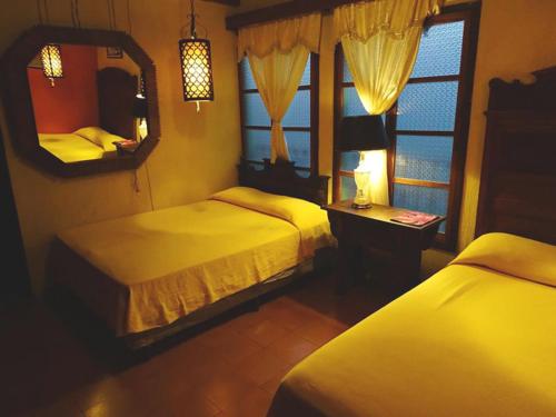 a bedroom with two beds and a mirror at Posada San Sebastian in Antigua Guatemala