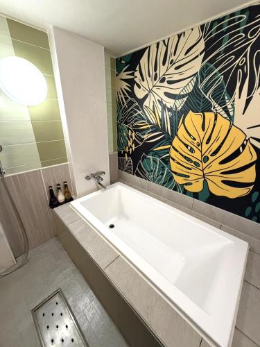a white bath tub in a bathroom with a flower mural at Hotel First (Adult Only) in Ikeda