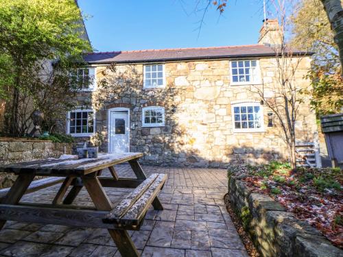 a picnic table in front of a stone building at Woodland Cottage in Llangollen