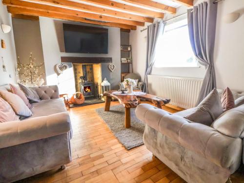 a living room with two couches and a table at Woodland Cottage in Llangollen