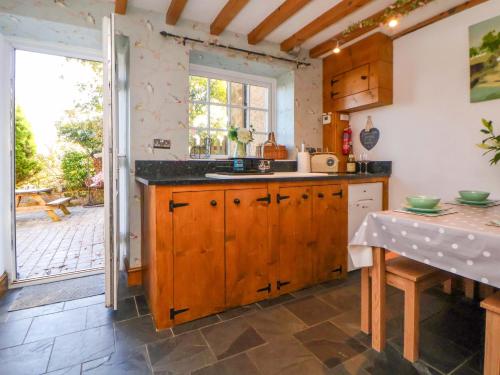 a kitchen with wooden cabinets and a large window at Woodland Cottage in Llangollen