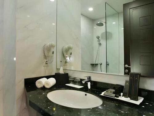 um banheiro com uma pia e um espelho grande em pyramid suites Hotel em Banjarmasin