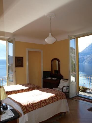 a bedroom with two beds and a view of the water at Hotel Olivedo in Varenna