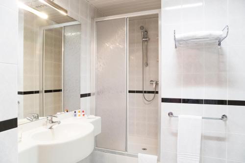 a white bathroom with a shower and a sink at Hotel Mara in Ortona