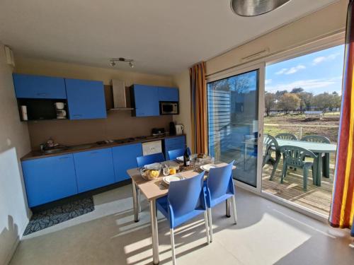 a kitchen with blue cabinets and a table with chairs at Cottage Rembrandt in Chaveignes