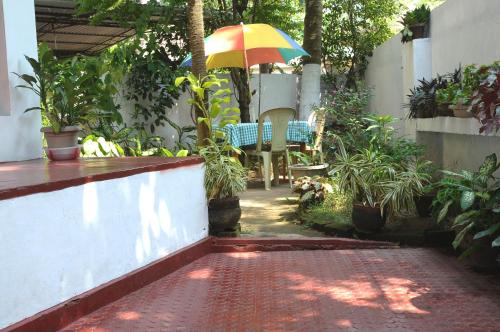 a patio with a table and an umbrella at Maison Casero Home Stay in Cochin