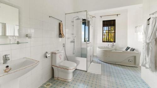 un bagno bianco con vasca, WC e lavandino di Entebbe Hotel a Entebbe
