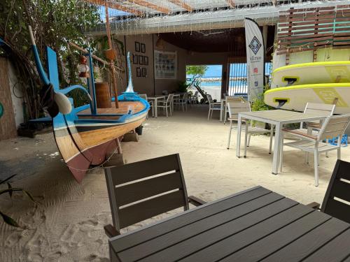 um restaurante com um barco, mesas e cadeiras em Alimas Holiday Retreat Maldives em Felidhoo