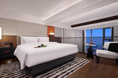 a bedroom with a large white bed and a chair at Yuezhi Hotel Longnan Yingbin Avenue Branch in Magutang