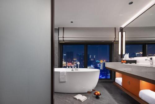 a bathroom with a large tub and a city skyline at Yuezhi Hotel Longnan Yingbin Avenue Branch in Magutang