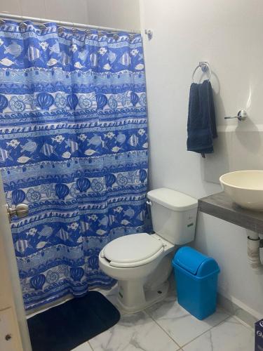 a bathroom with a toilet and a blue shower curtain at Departamento Premium en Acapulco in La Sabana