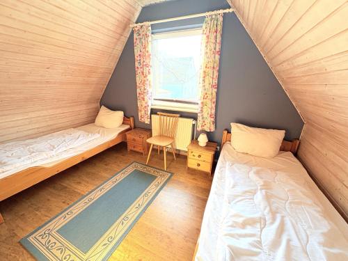 an attic bedroom with two beds and a window at Ferienhaus Nele - ein strandnahes, einfaches Haus in Breege