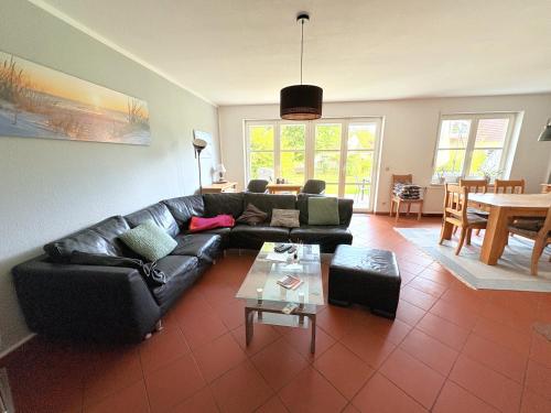 Ferienhaus zum Kranichblick في Garz: غرفة معيشة مع أريكة جلدية سوداء وطاولة