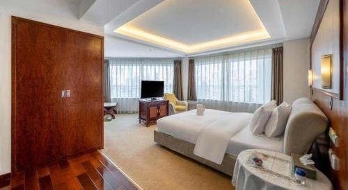 a hotel room with a large bed and a television at Expo Garden Hotel in Kunming