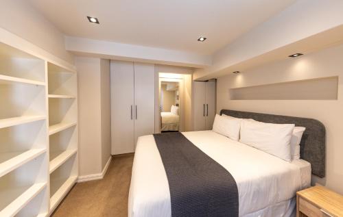 Historic Mutual Heights CBD Loft w Pool & Gym في كيب تاون: غرفة نوم بسرير كبير ورفوف