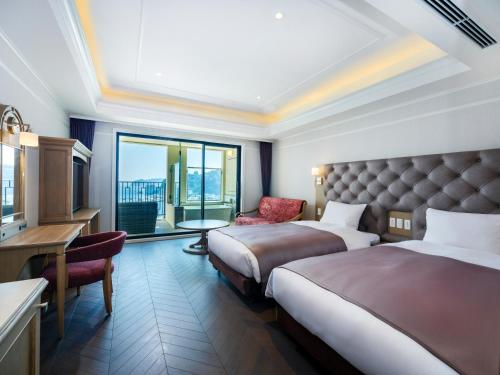 a hotel room with two beds and a desk at La Vista Atami Terrace in Atami