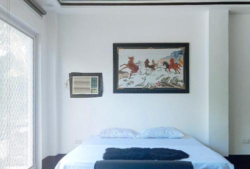 ein Schlafzimmer mit einem Bett und einem Gemälde an der Wand in der Unterkunft KrizLion Hotel in Hinatuan