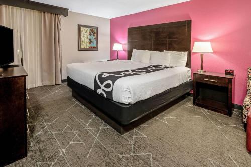 Un dormitorio con una cama grande y una pared rosa en La Quinta by Wyndham Dallas I-35 Walnut Hill Ln, en Dallas