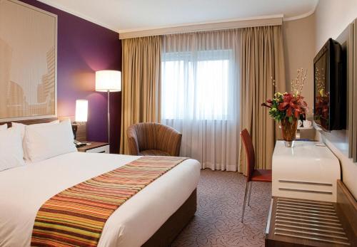 a hotel room with a bed and a television at Garden Court Sandton City in Johannesburg