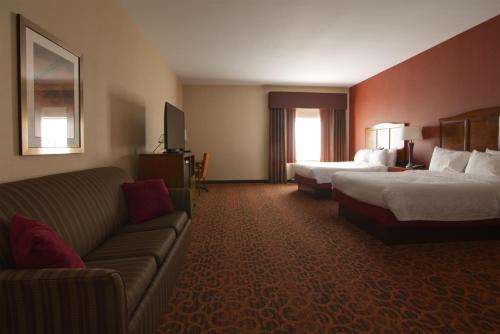 a hotel room with two beds and a couch at Hampton Inn Bangor in Bangor