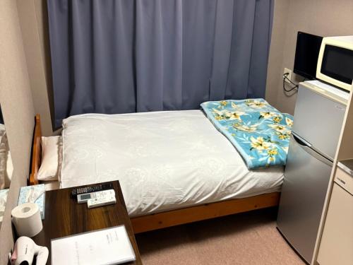 a small bedroom with a bed with a blue curtain at ドリームビレッジエンシン in Wada