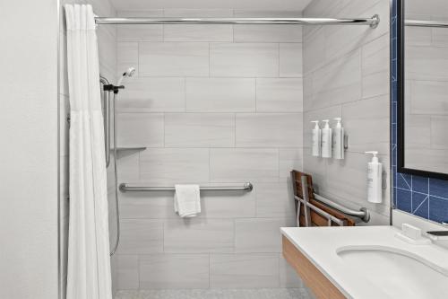 Un baño blanco con ducha y lavabo. en Spark By Hilton North Little Rock, en North Little Rock