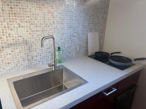 a kitchen counter with a sink and two frying pans at Aparthotel STATUS SUSUKINO 102 in Sapporo