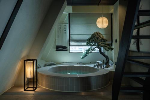 a bathroom with a large tub with a tree in it at Stay Passport Sapporo Ryokan Seoul Hongdae in Seoul