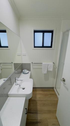 a white bathroom with a sink and a mirror at Griffith Tourist Caravan park in Griffith