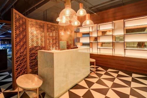 a lobby with a counter and chairs and chandeliers at Sunday Hotel Arshika Sunset Road in Kuta