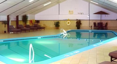 a large swimming pool in a large room with tables and chairs at Garden Plaza Hotel in Passaic Junction