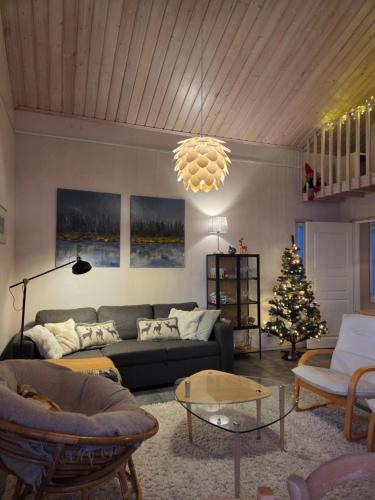 a living room with a couch and a christmas tree at Villa Ateljee in Rovaniemi