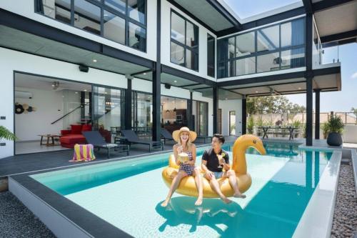 a man and a woman sitting on a plastic rendition of a house at LUXURY 4BR Oxygen Pool Villa Near Nai Harn Beach - Sunset Garden 7 in Rawai Beach