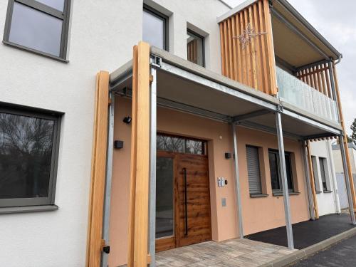 a house with a wooden door and a balcony at Genuss Apartment in Purbach am Neusiedlersee