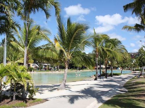 a beach with palm trees and people in the water at Tropic Haven in Airlie Beach