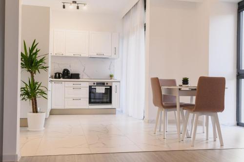 eine Küche mit weißen Schränken und einem Tisch und Stühlen in der Unterkunft Malvina Apartments Cazare Mures in Târgu Mureș