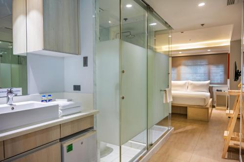 uma casa de banho com um lavatório, um chuveiro e uma cama. em The Mini Suites Eton Tower Makati em Manilla