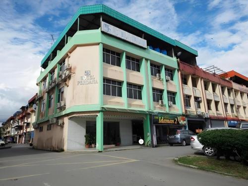a green and white building with cars parked in front of it at Hotel Perdana in Lawas