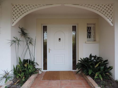 a white front door of a house with plants at Chambres d'Hôtes Villa La Louisiane in Arès
