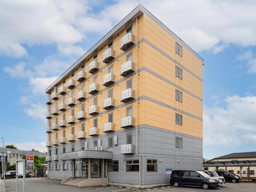 a tall yellow building with cars parked in a parking lot at Comfort Inn Kofu Showa Inter in Kofu