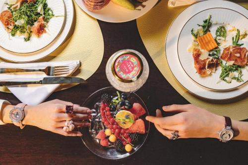 Dos personas sentadas en una mesa con un plato de comida. en Grand Hotel Kempinski Riga, en Riga